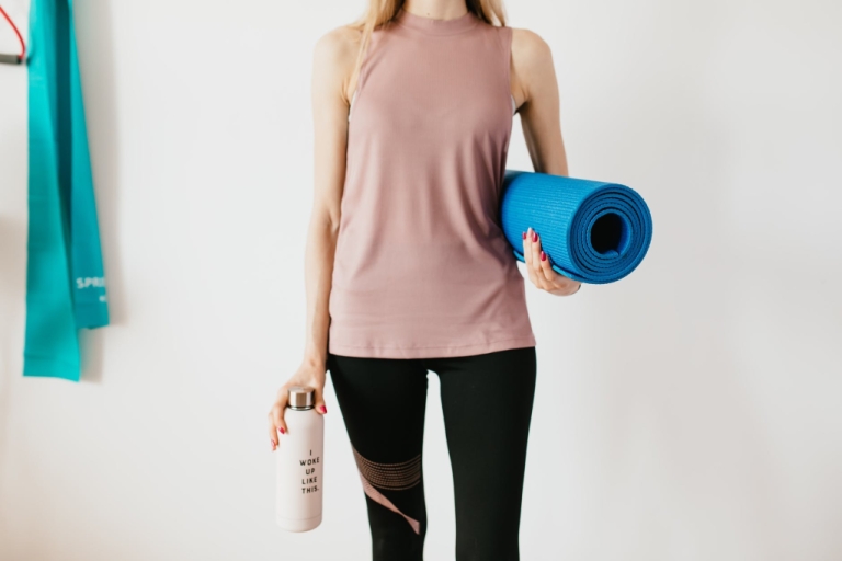 A woman holding a yoga mat